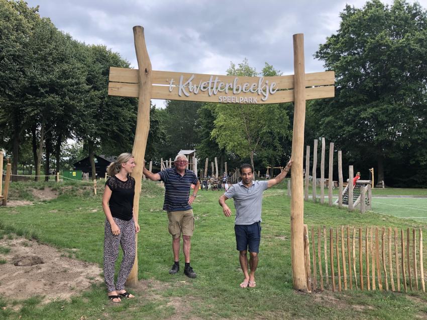 3 personen staan bij de houten ingang van de speeltuin